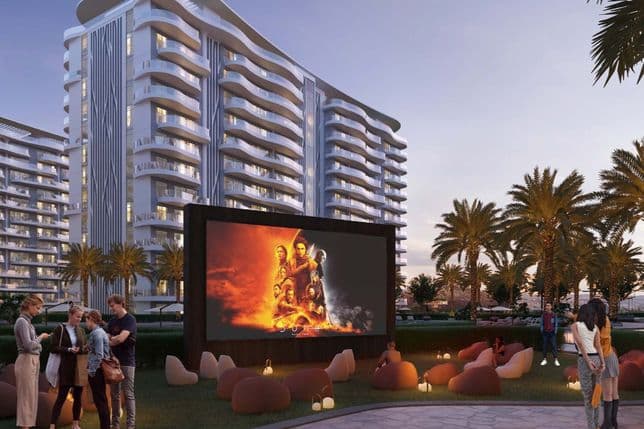 Outdoor movie screening at dusk with modern buildings, palm trees, and groups of people gathered around beanbags under soft lighting.