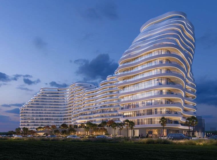 Night view of La Mazzoni by Luxe at Al Marjan Island RAK with curved illuminated facade and modern design