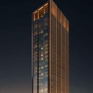 Tall, modern skyscraper with glass facade and warm lighting, set against a dark night sky between two vertical orange pillars.