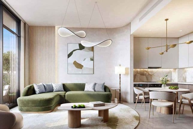 Bright modern open-plan living room and kitchen with green curved sectional, round wooden coffee table, abstract wall art and gold pendant lights.