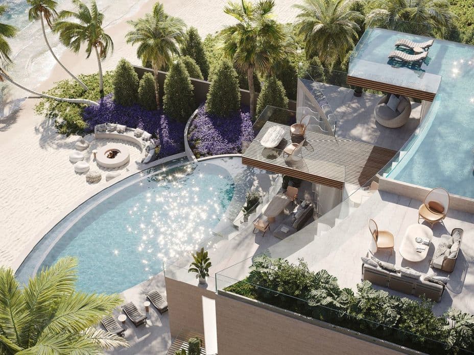 Luxurious beachfront villa with two-tiered infinity pools, palm trees, outdoor seating, a fire pit, and ocean views on a sunny day.