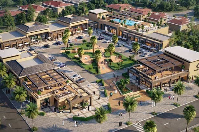Aerial view of a modern shopping complex with parking, outdoor seating, palm trees, and surrounding greenery.