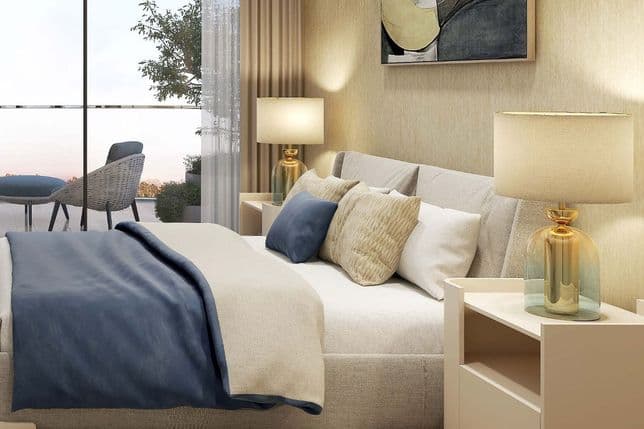 Cozy bedroom with a beige bed, blue and beige pillows, two lamps, abstract art, and balcony with outdoor seating.