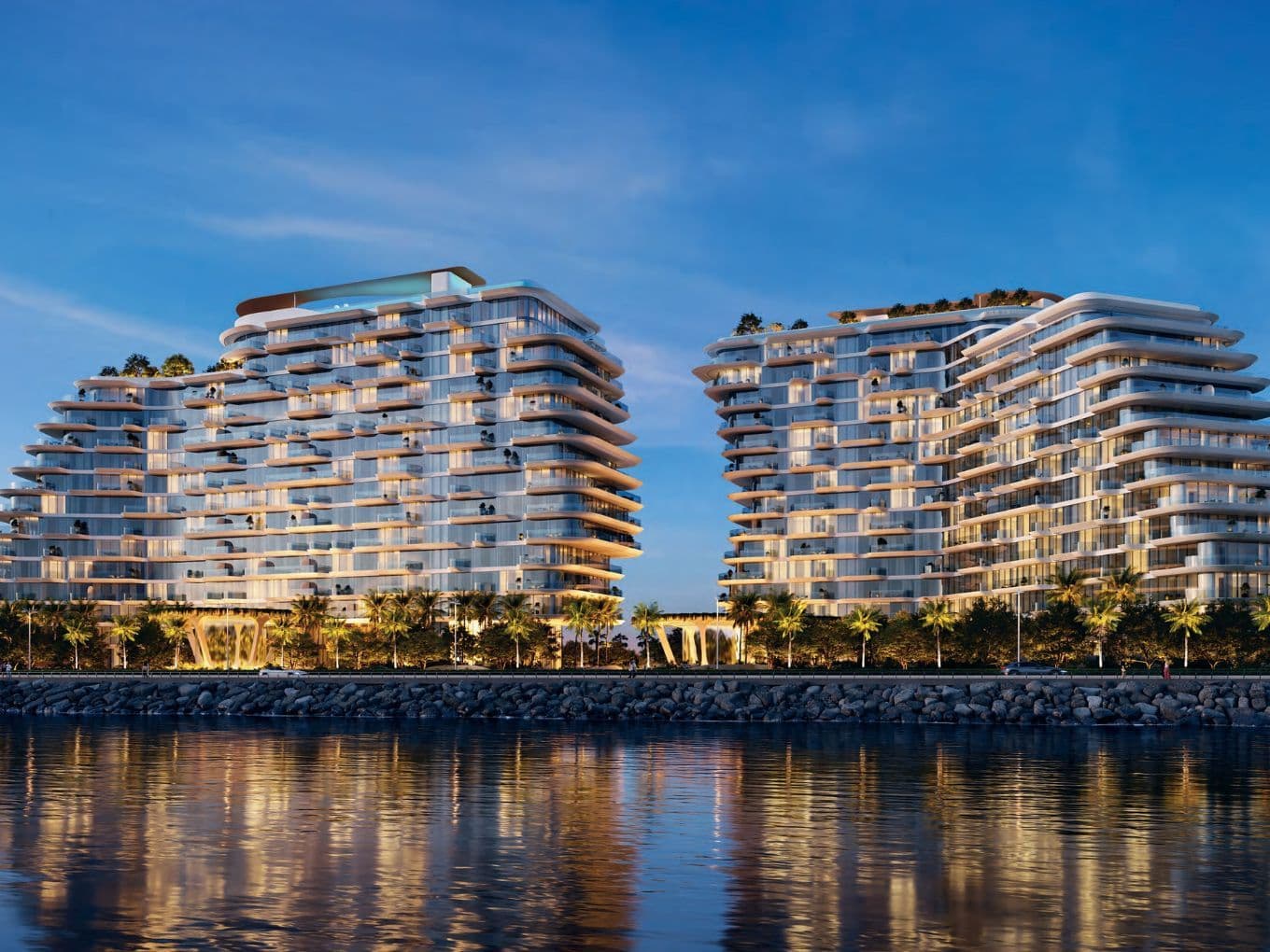 Dusk view of Passo twin towers with warm lighting reflecting on the water, framed by palm trees and modern design.