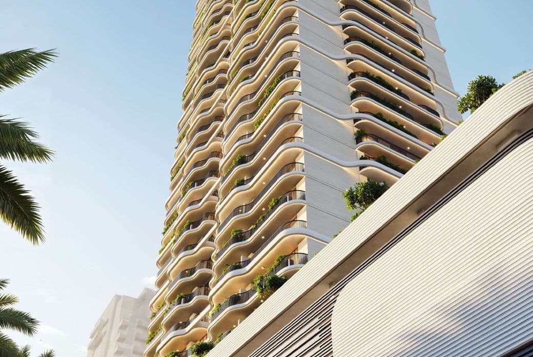 Upward view of ALTA V1EW’s distinctive curved façade with layered balconies, lush greenery, and architectural detailing under a clear sky.