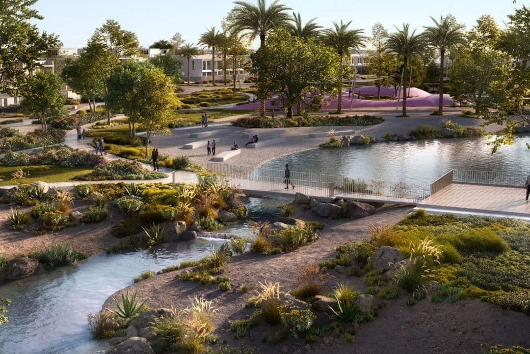 A landscaped park at Vindera at The Valley featuring walking paths, water streams, greenery, and residents enjoying the outdoor spaces.