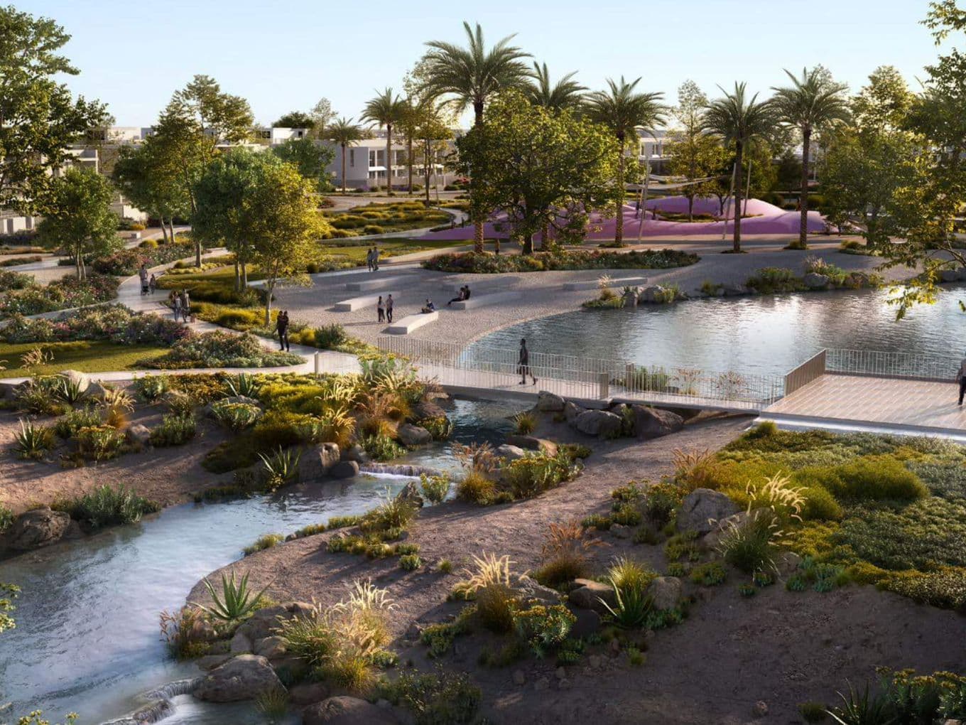 Ein begruenter Park in Vindera at The Valley mit Spazierwegen, Wasserlaeufen, viel Gruen und Bewohnern, die die Aussenbereiche nutzen.