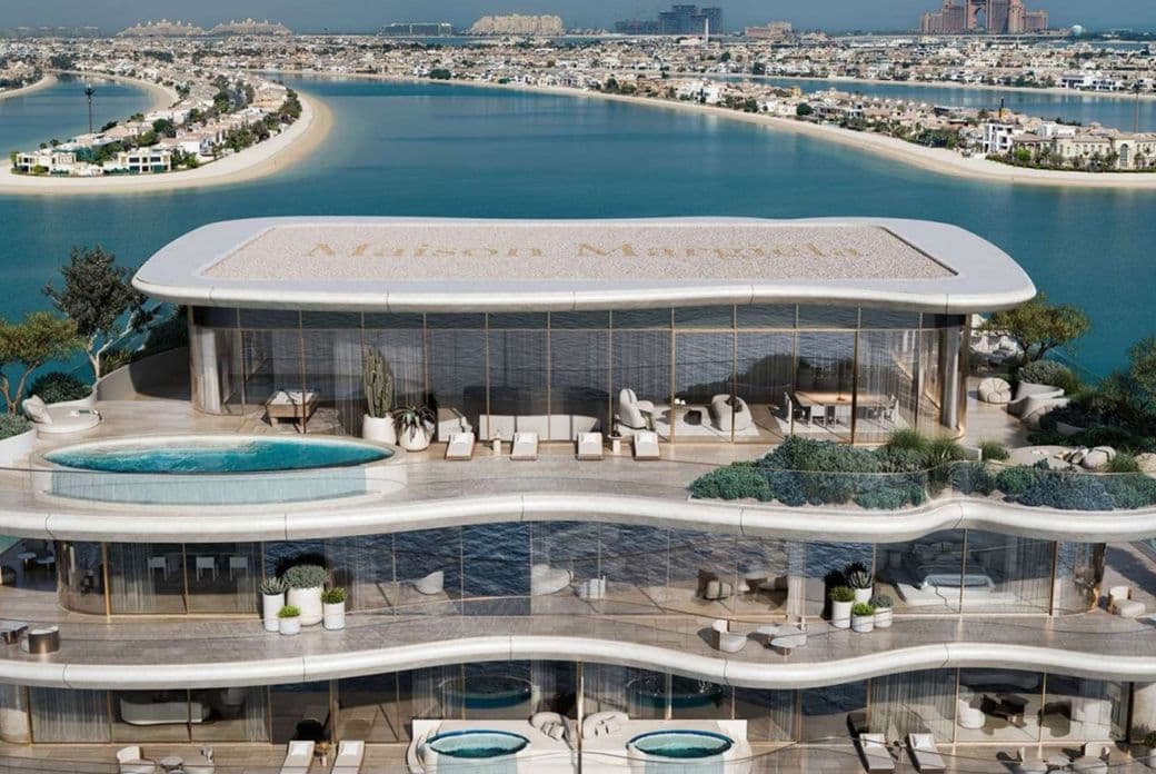 Luxurious multi-story beachfront building with pools, terraces, and panoramic ocean views, set against a backdrop of a coastal cityscape.