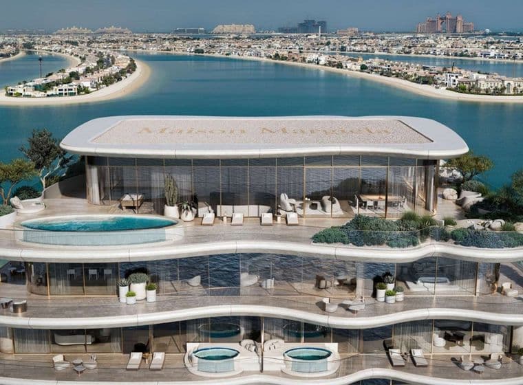 Luxurious multi-story beachfront building with pools, terraces, and panoramic ocean views, set against a backdrop of a coastal cityscape.