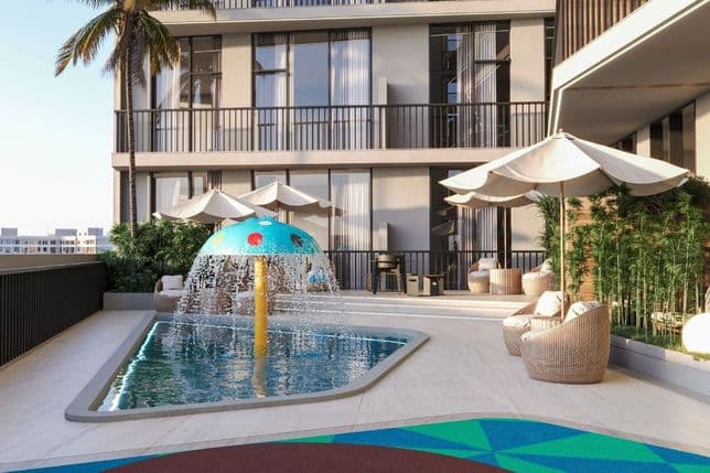 Rooftop patio with small splash pool, mushroom-shaped fountain, wicker chairs, umbrellas, and surrounding tall building.