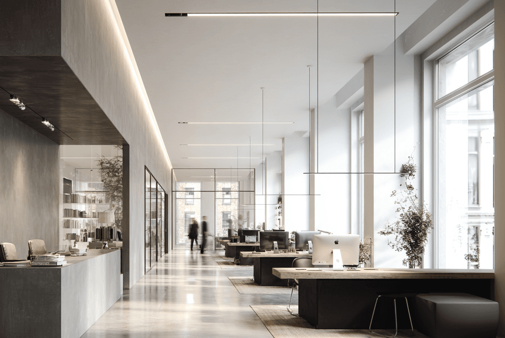 Modern office interior with sleek desks, large windows, minimalistic design, and soft lighting. Two blurred figures walk in the background.