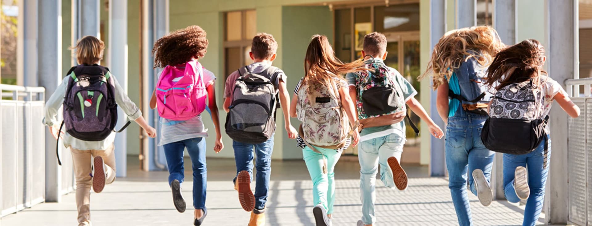 A group of school children with backpacks joyfully running.
