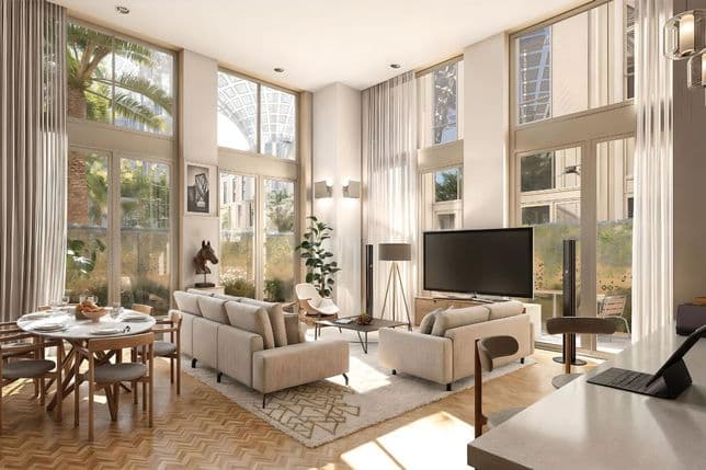 Bright contemporary living room with double-height ceilings, large floor-to-ceiling windows, elegant neutral furnishings, dining table, and view of Expo City’s shaded canopies outside.