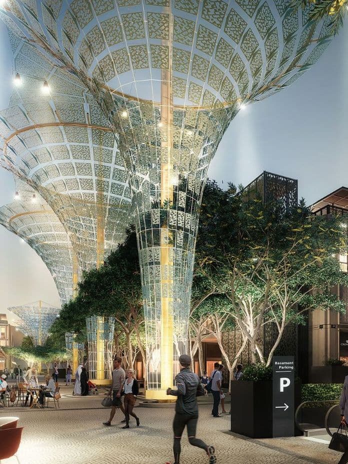 Evening scene at Expo City Dubai with people dining outdoors beneath futuristic solar canopy structures, surrounded by boutique shops, cafés, and illuminated architectural façades.