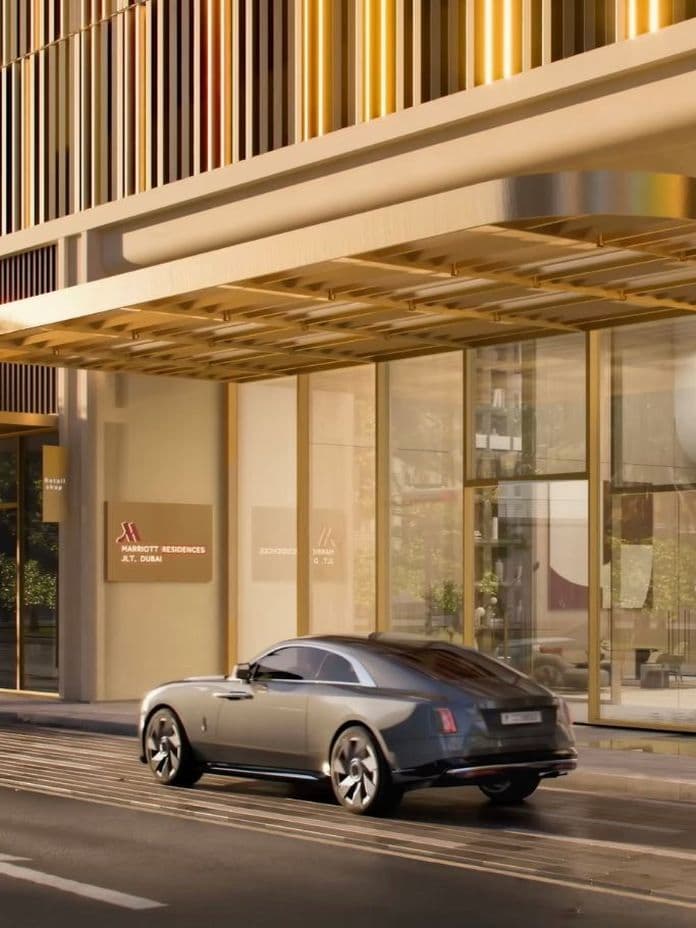 Street-level view of Marriott Residences JLT entrance with luxury car parked in front, golden façade details, and branded signage.