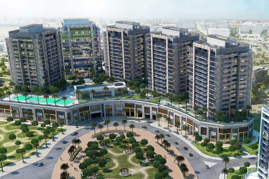 Aerial view of Al Sayyah Residence in Arjan, Dubai, showing multiple modern high-rise apartment towers with glass façades, rooftop pools, landscaped gardens, and retail spaces at the podium level. The surrounding area includes tree-lined walkways, green parks, and nearby residential developments