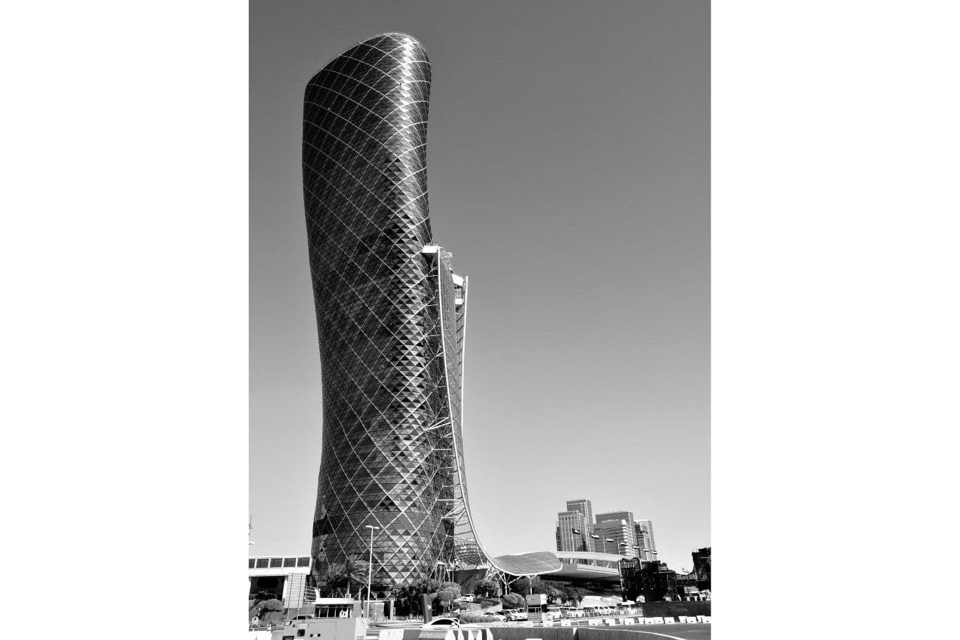 Black and white image of a modern, twisting skyscraper with a diamond-patterned facade, set against a clear sky.