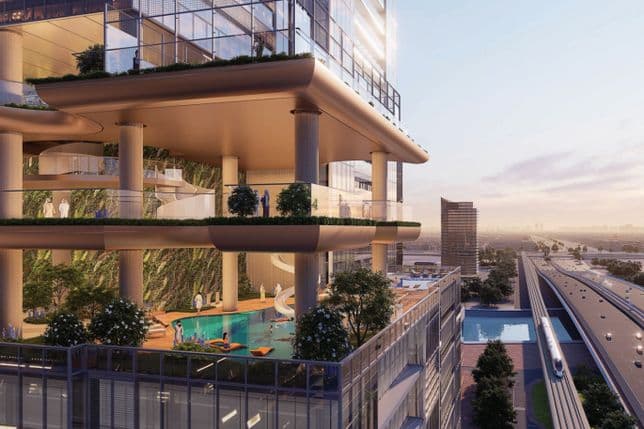 Modern multi-level building with greenery, pool, and open terraces. Adjacent to train tracks, city skyline visible at sunset.