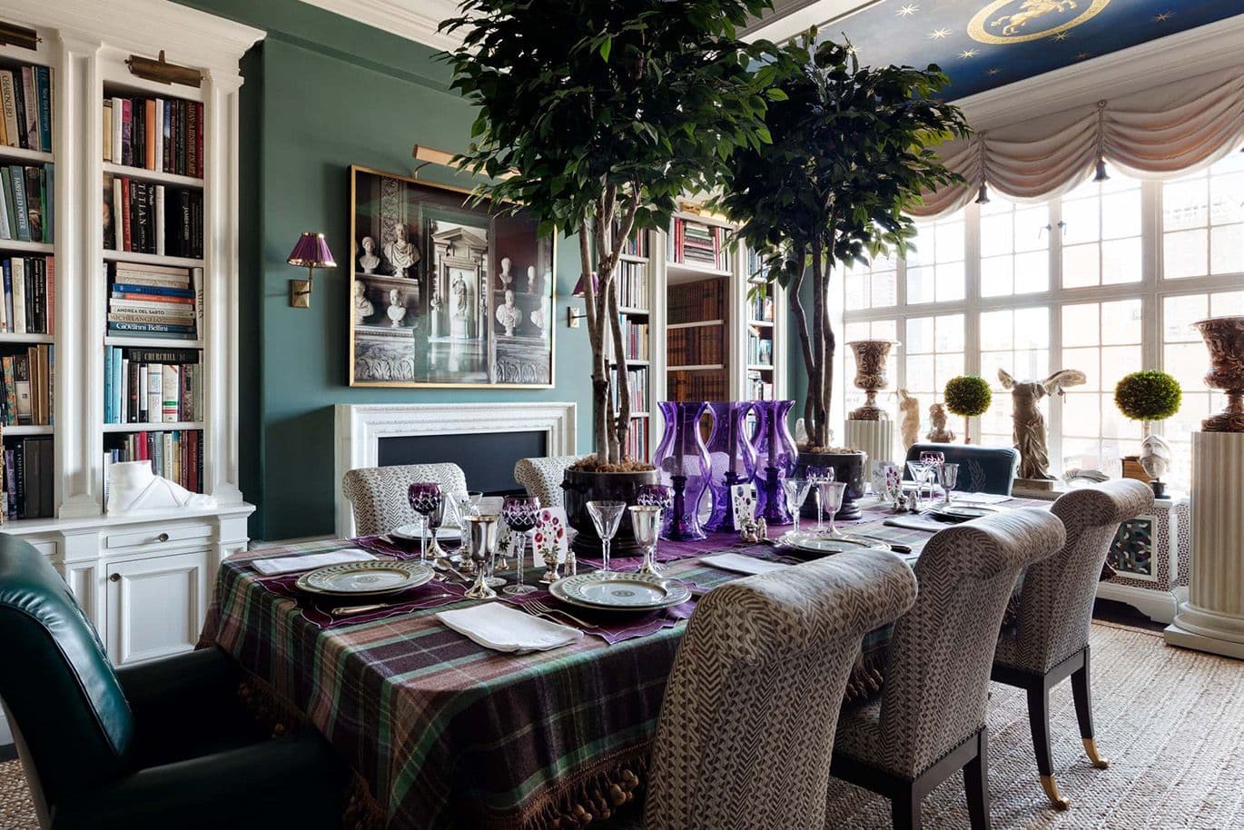 Elegant dining room with checkered tablecloth, purple glasses and artistic decoration. Bookshelves and large windows give the room a sophisticated touch.