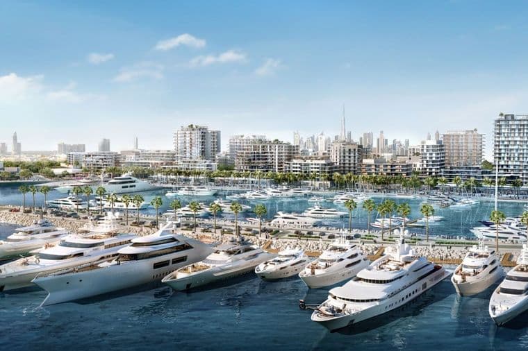 Luxury yachts docked in the marina at Mina Rashid, Dubai, with modern mid-rise waterfront residences, palm-lined promenades, and the city skyline, including Burj Khalifa, visible in the background under a clear blue sky.          Ask ChatGPT