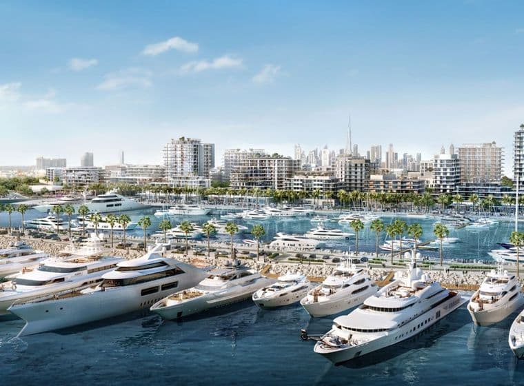 Luxury yachts docked in the marina at Mina Rashid, Dubai, with modern mid-rise waterfront residences, palm-lined promenades, and the city skyline, including Burj Khalifa, visible in the background under a clear blue sky.          Ask ChatGPT
