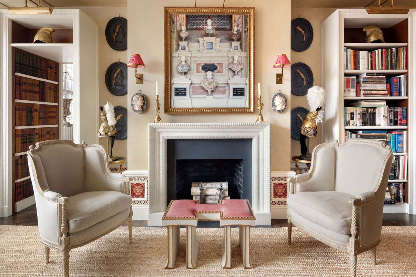 Elegant living room with two armchairs, a decorative fireplace, framed artwork and bookshelves. Neutral tones and eclectic furnishings accentuate the space.