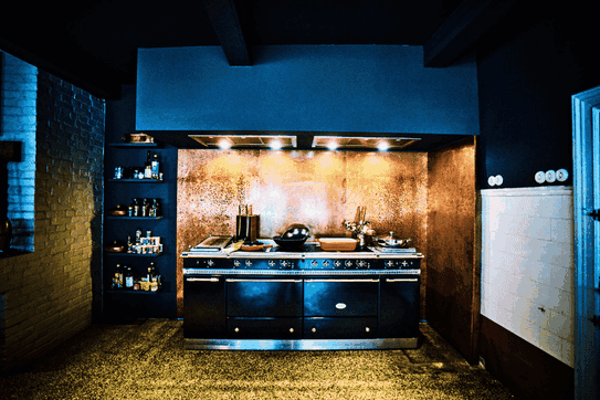 Kupferne Rückwand und schwarzer Herd mit schwarzem Abzug