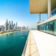 View from a modern building's terrace overlooking a city skyline and waterfront under a clear blue sky.