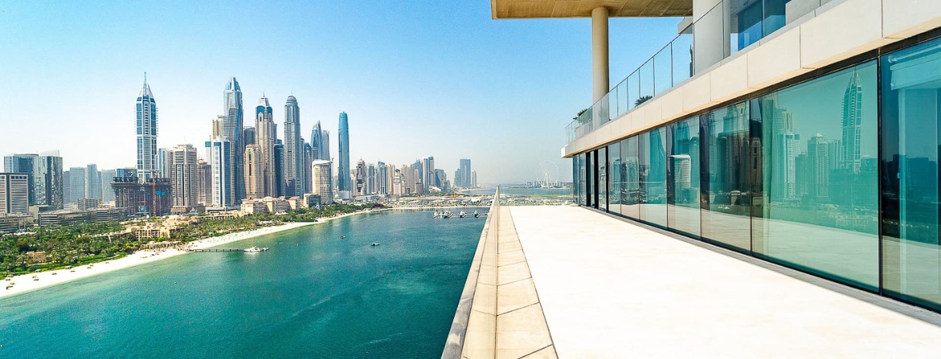 View from a modern building's terrace overlooking a city skyline and waterfront under a clear blue sky.