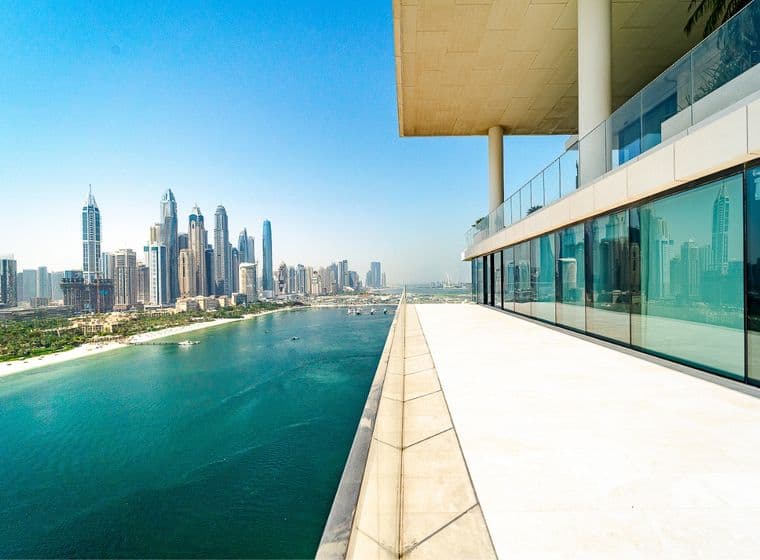 View from a modern building's terrace overlooking a city skyline and waterfront under a clear blue sky.