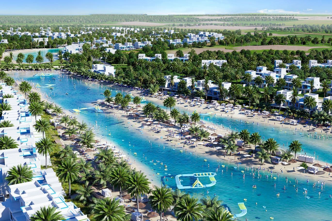 Aerial view of Damac Lagoons with turquoise water, palm trees, white buildings, and people enjoying water activities and sunbathing.