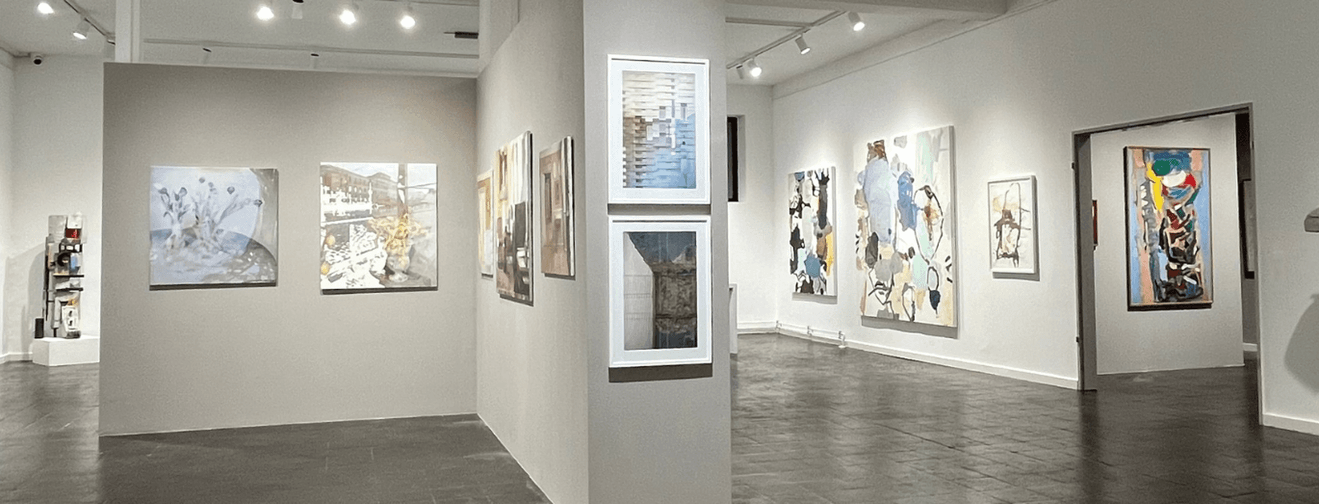 Gallery with white walls and pictures on the wall, a partition in the middle with more pictures