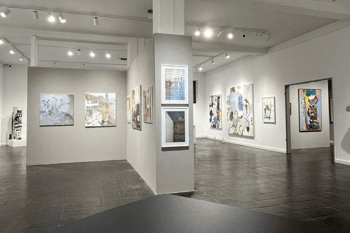 Galerie mit weißen Wänden und Bildern an der Wand, eine Trennwand in der Mitte ermöglicht weitere Bilder aufzuhängen