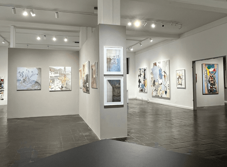 Galerie mit weißen Wänden und Bildern an der Wand, eine Trennwand in der Mitte ermöglicht weitere Bilder aufzuhängen