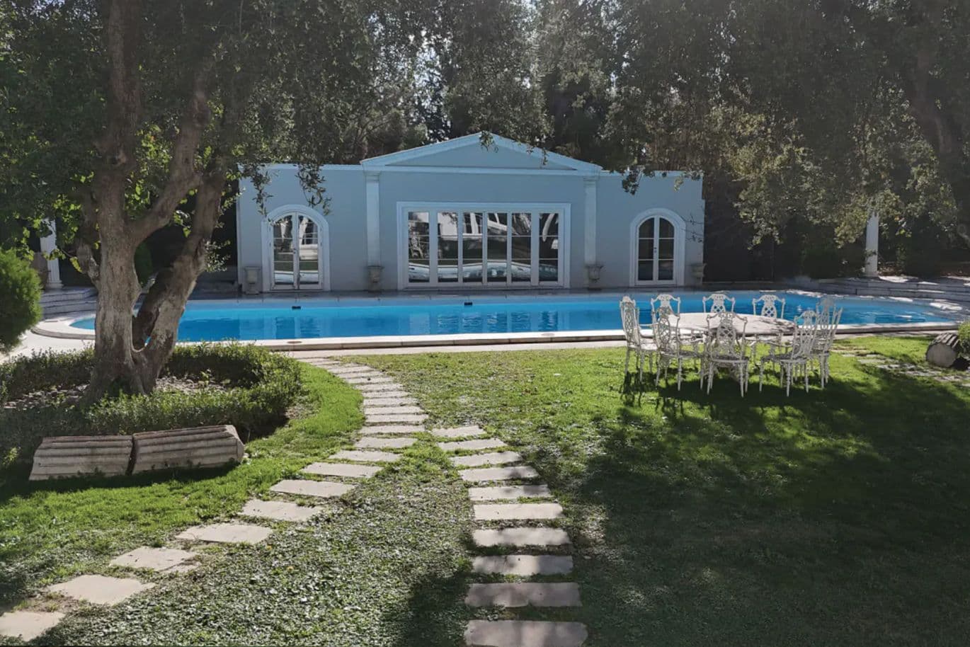 Κήπος πολυτελούς κατοικίας με πισίνα και νεοκλασικό κτίσμα στην Αθήνα, ιδανικός για εκδηλώσεις και πολυτελή διαβίωση.