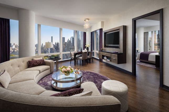 Elegant living room with panoramic windows, city view, round sofa, and access to the bedroom.