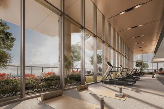 Modern gym with large windows, treadmills, yoga mats, and weights. Outdoor view features plants and a clear sky.