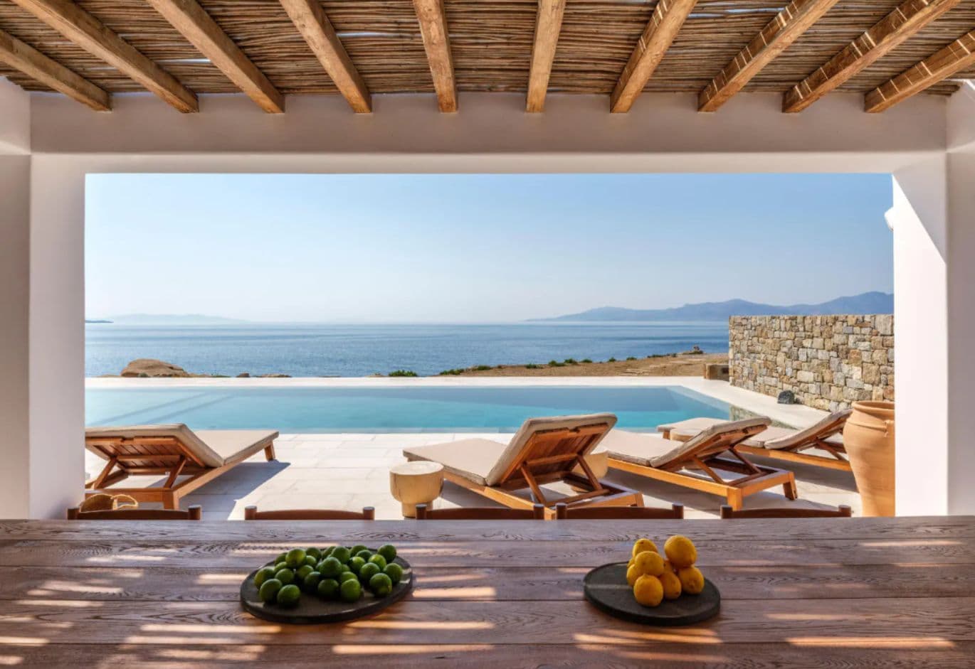 Seaside terrace with infinity pool, sun loungers, and panoramic ocean view