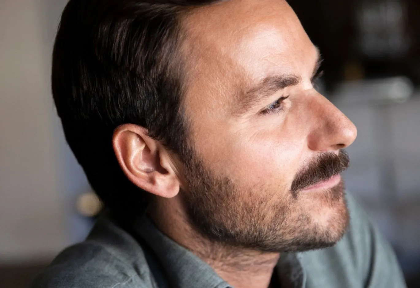 Side profile portrait of a man with short brown hair, beard, and mustache.