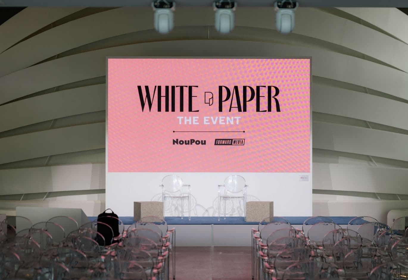 Conference stage prepared for White Paper The Event with presentation screen, seating, and audience area before the session