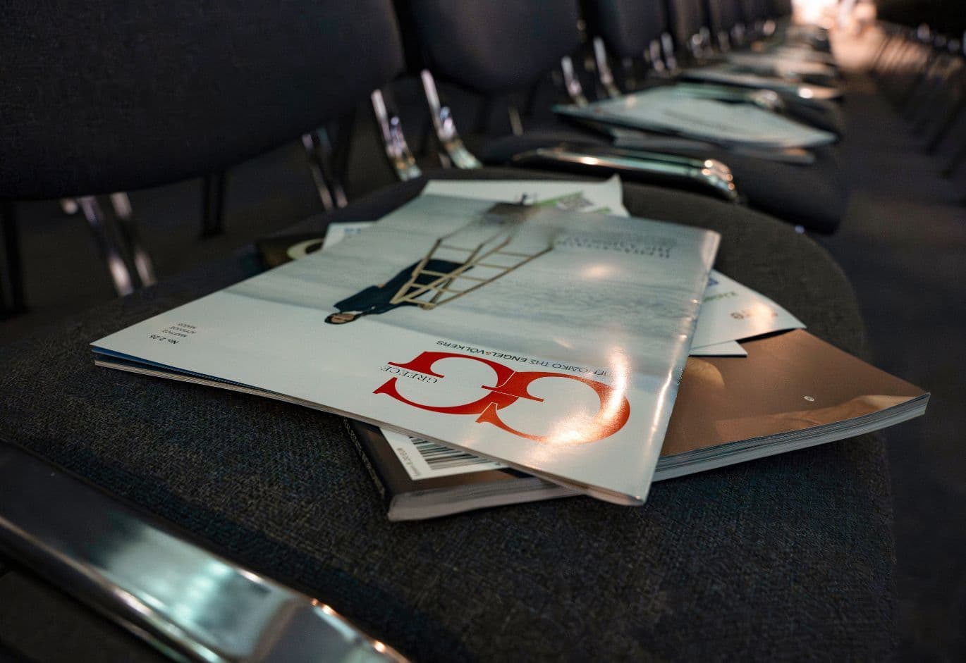 Real estate industry magazines and event brochures placed on conference seating before the forum