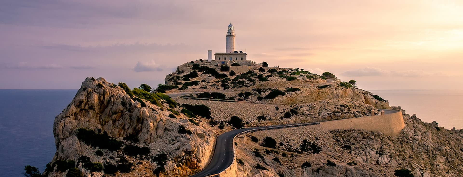 Leuchtturm auf einer felsigen Klippe bei Sonnenuntergang.