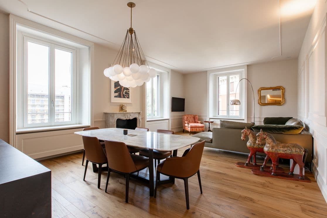 Modernes Esszimmer mit Marmortisch, braunen Stühlen, einem einzigartigen wolkenartigen Kronleuchter und vielseitiger Einrichtung, darunter ein rotes Schaukelpferd.