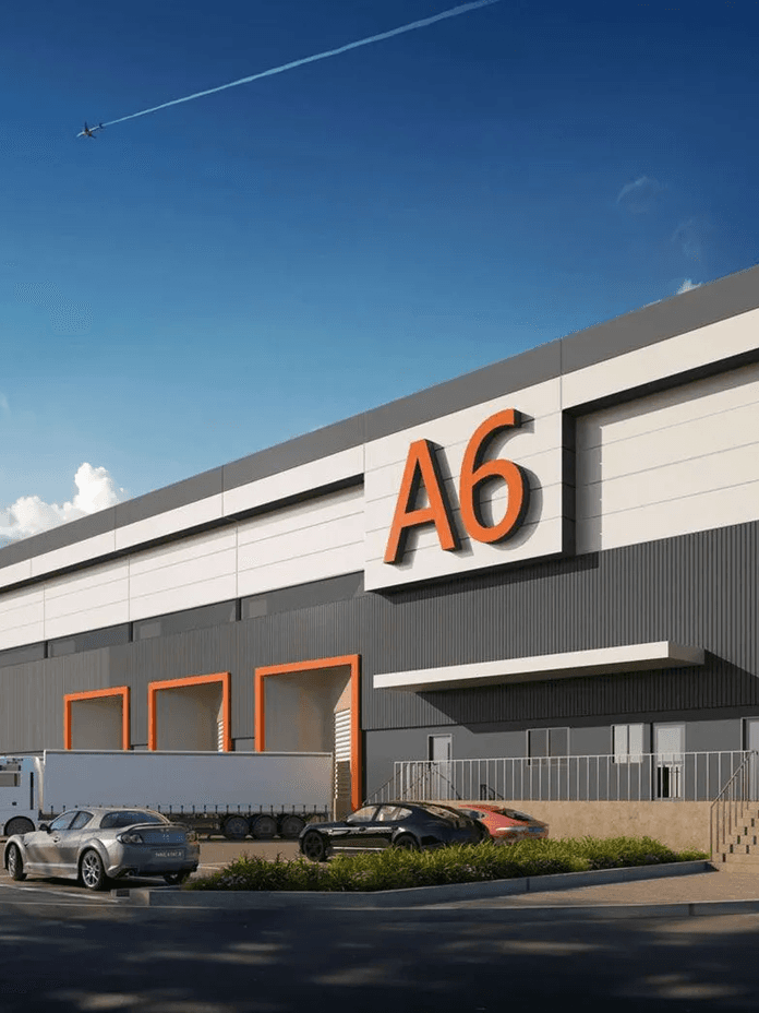 Large industrial warehouse labeled 'A6', with multiple loading docks, parked trucks, and a clear blue sky overhead.