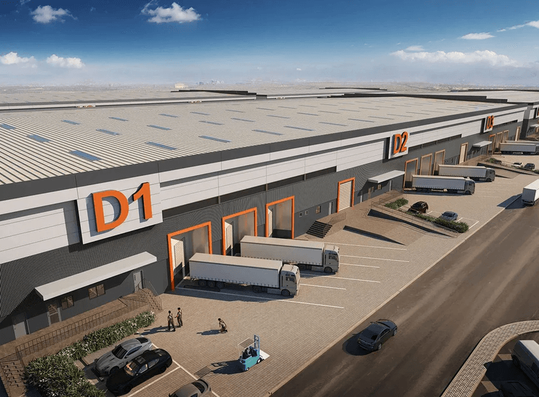 Luftaufnahme eines großflächigen Industrie und Lagerhallenkomplexes mit mehreren Laderampen, Lkw und Parkflächen unter klarem blauem Himmel.