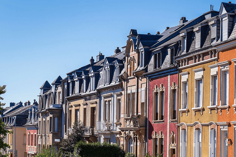 Rangées de maisons de ville colorées avec des lucarnes sous un ciel bleu clair.