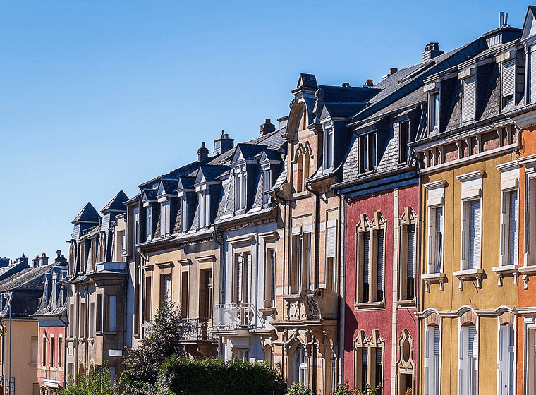 Rangées de maisons de ville colorées avec des lucarnes sous un ciel bleu clair.