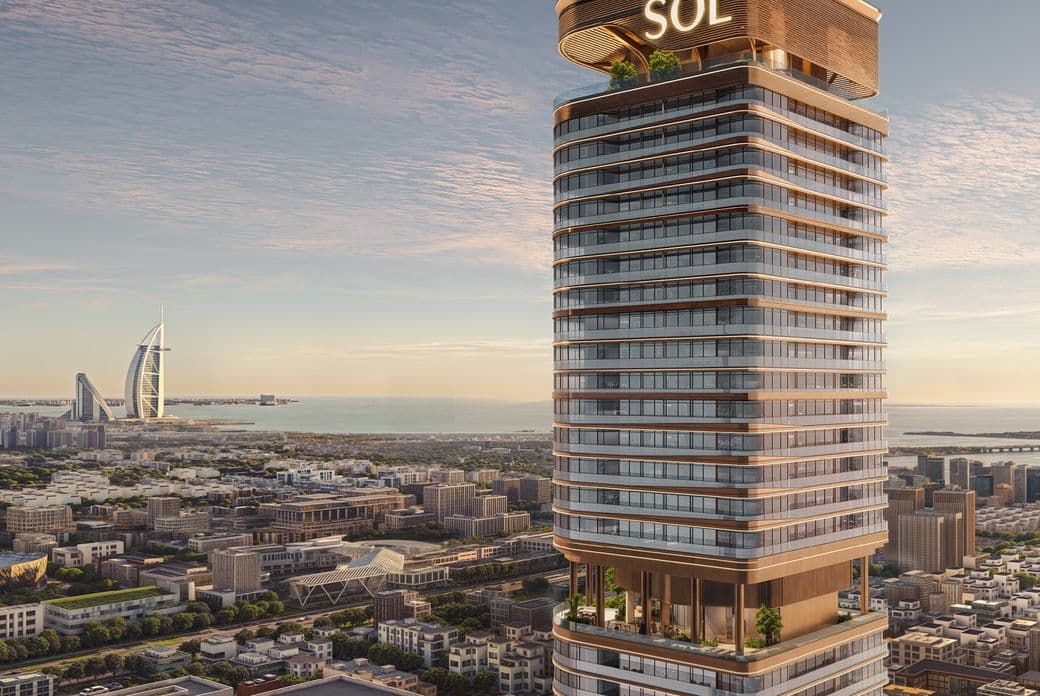 Modern skyscraper labeled "SOL" against a city skyline at sunset, with the sea and distinctive sail-shaped building in the background.