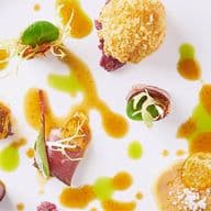 Ein Gourmetgericht, kunstvoll auf einem weißen Teller angerichtet.