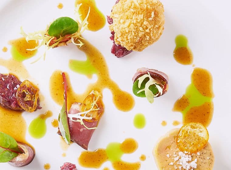 Ein Gourmetgericht, kunstvoll auf einem weißen Teller angerichtet.